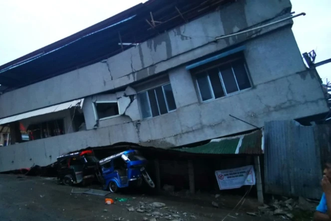 Des habitants observent une maison détruite avec un véhicule coincé dessous après un puissant séisme, à Padada dans la province de Davao del Sur sur l'île de Mindanao aux Philippines le 15 décembre 2019