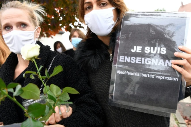 Deux femmes portent des roses et des messages en faveur de la liberté d'expression le 17 octobre 2020 à Conflans-Sainte-Honorine