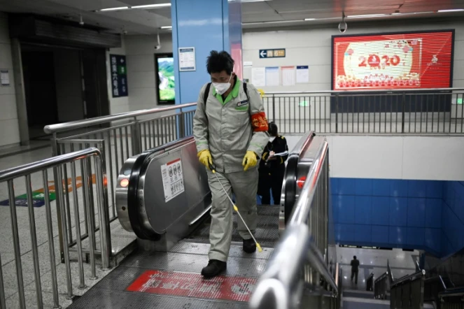 Un employé muni d'un masque de protection vaporise un produit désinfectant dans une station de métro, à Pékin le 31 janvier 2020