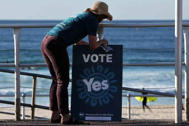 Un volontaire tient une pancarte devant un bureau de vote à Bondi Beach à Sydney le 14 octobre 2023