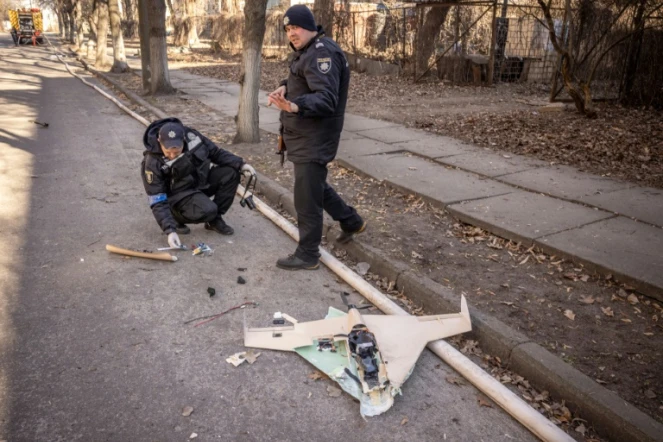 Des policiers ukrainiens inspectent un drone russe abattu dans les environs de l'Académie nationale des sciences, touchée par une frappe, à Kiev, le 22 mars 2022