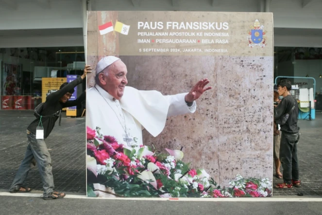 Des ouvriers installent le 3 septembre 2024 un panneau d'affichage pour la messe qui sera dirigée par le pape François au stade Gelora Bung Karno à Jakarta