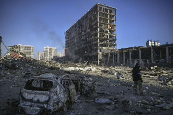 Un militaire ukrainien devant le centre commercial Retroville dévasté par un bombardement, à Kiev le 21 mars 2022