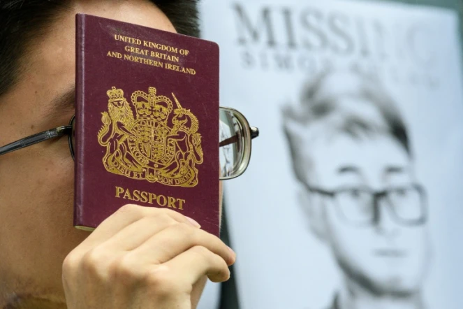 Un militant brandit un passeport britannique devant un portrait de Simon Cheng, le 21 août 2019 devant le consulat de Grande-Bretagne à Hong Kong