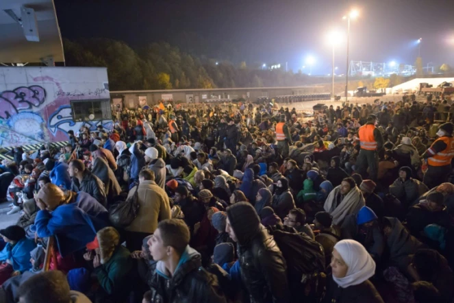 Migrants et réfugiés attendent de monter dans un bus le 23 octobre 2015 à Sentilj à la frontière entre la Slovénie et l'Autriche
