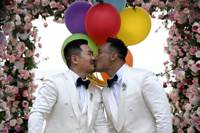 Les Chinois Song Jihan (g) et Wang Zengyi s'embrassent lors de la cérémonie de leur mariage près de Pattaya, dans la province de Chonburi, le 31 mai 2025 en Thaïlande