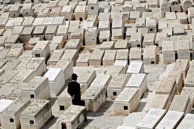 Un homme se recueille sur une tombe dans le cimetière juif du Mont des Oliviers, en face de la Vieille ville de Jérusalem, le 9 septembre 2018