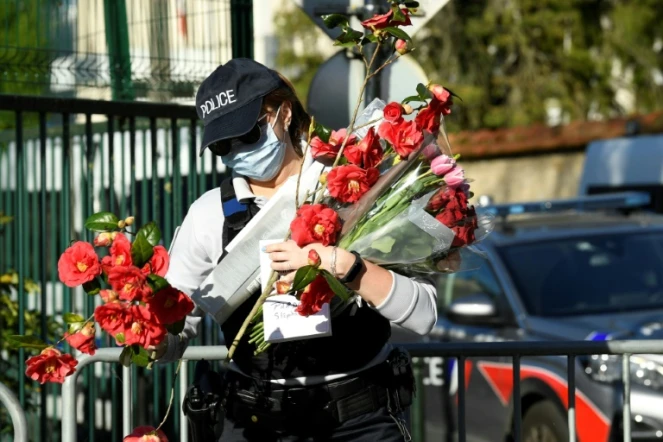 Une policière ramasse des fleurs apportées en hommage à Stéphanie Monfermé, le 26 avril 2021 devant l'h?'tel de police de Rambouillet