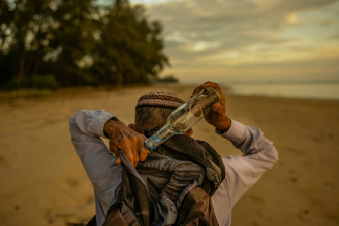 Photo du 16 septembre 2020 de Tengku Mohamad Ali Mansor en train de ramasser des bouteilles sur une plage de l'est de la Malaisie.