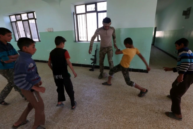 Des garçons jouent au foot dans leur école avec un soldat des forces irakiennes, le 12 novembre 2016, dans le village de Jarif, à environ 45 kilomètres au sud de Mossoul