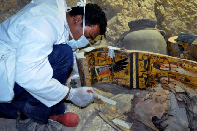 Un membre d'une équipe archéologique égyptienne travaille sur un cercueil en bois découvert dans une tombe de 3.500 ans dans la nécropole de Draa Abul Nagaa, près de Louxor, le 18 avril 2017