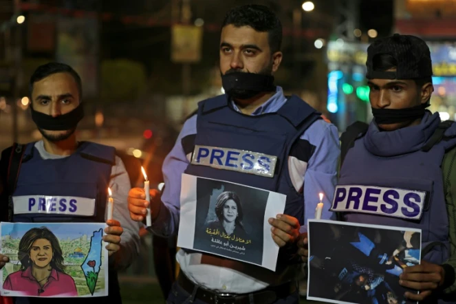 Des journalistes tenant des bougies à la main et des posters de la journaliste palestinienne tuée Shireen Abu Akleh, lors d'une cérémonie à Rafah dans la bande de Gaza, le 11 mai 2022 
