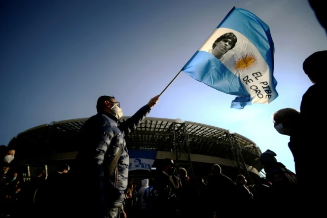 Un homme avec un drapeau orné d'une photo de Diego Maradona devant le stade de Naples le 26 novembre 2020