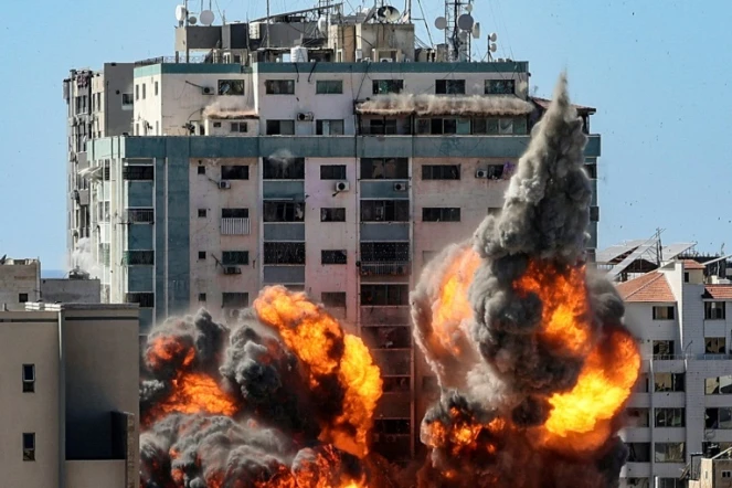 Des boules de feu jaillissent d'un bâtiment qui abritait les locaux de médias internationaux, pulvérisé par une frappe israélienne, le 15 mai 2021 à Gaza 