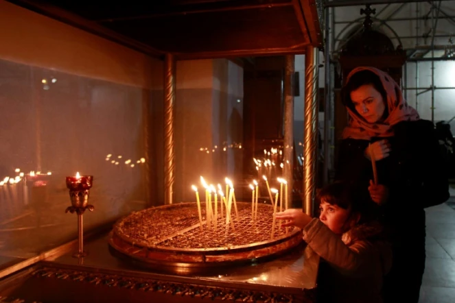 Une chrétienne et son fils allument des cierges le 20 décembre 2016 dansl'Eglise de la Nativité, à Béthléem en Cisjordanie, où Jésus-Christ est né selon la Bible