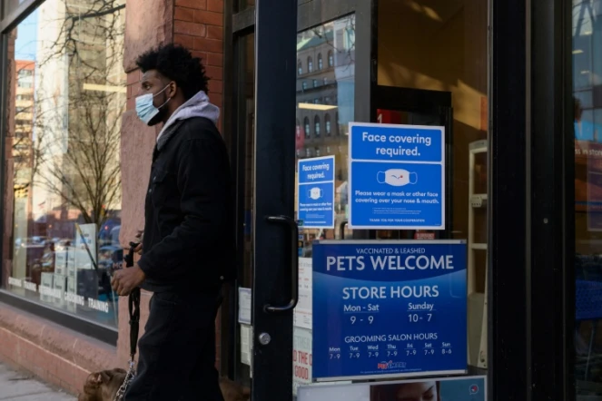 Un homme porte un masque de protection à la sortie d'une boutique, le 26 janvier 2022 à New York