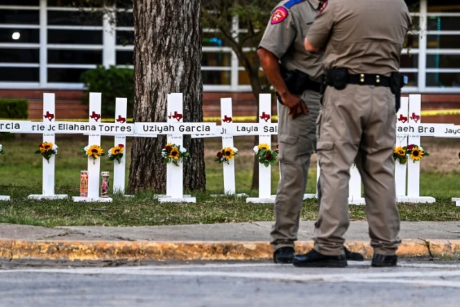 Des policiers se tiennent le 26 mai 2022 devant un mémorial de fortune pour les victimes de la fusillade dans l'école primaire Robb d'Uvalde au Texas