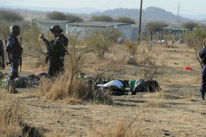 Des policiers devant des corps de manifestants sur lesquels ils ont ouvert le feu près de la mine de Marikana (Afrique dus Sud) le 16 août 2012