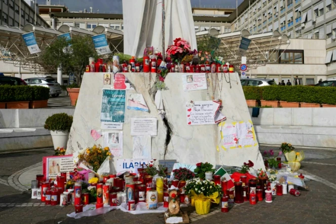 Des bougies, fleurs et messages déposés au pied de la statue de Jean-Paul II à l'extérieur de l'hôpital Gemelli à Rome où est soigné le pape François pour une pneumonie, le 10 mars 2025