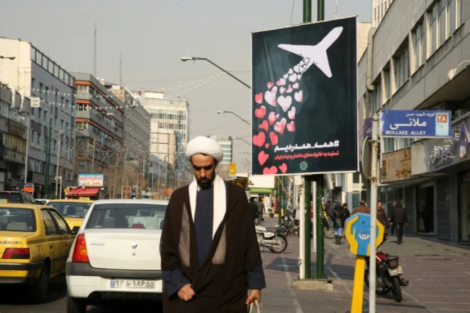 Un Iranien passe devant une affiche rendant hommage aux victimes du crash d'un avion ukrainien abattu "par erreur" par l'Iran, à Téhéran le 13 janvier 2020