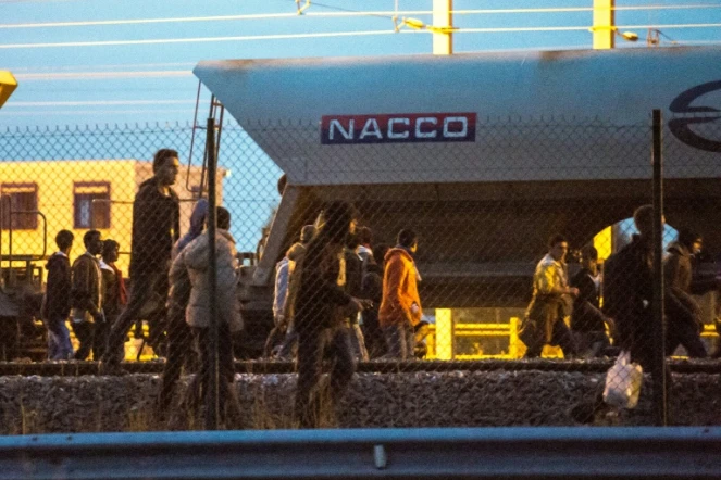 Des migrants marchent sur la voie ferrée en direction du terminal d'Eurotunnel le 11 août 2015 à Fréhun