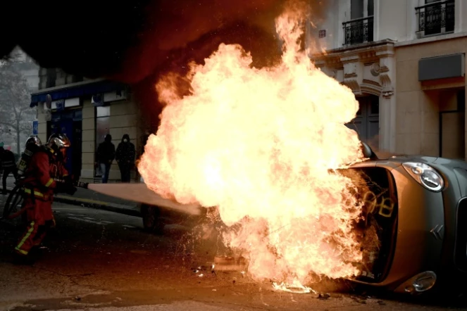 Un pompier tente d'éteindre le feu qui détruit une voiture place d'Italie à Paris, le 16 novembre 2019, en marge d'une manifestation des "gilets jaunes" 