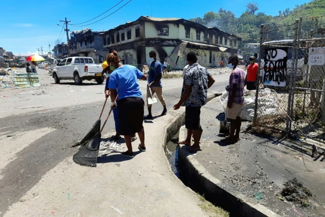 Des habitants nettoyent les rues après des émeutes meurtrières, le 28 novembre 2021 à Honiara, aux Iles Salomon