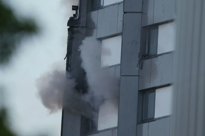 Une main tenant un tissu apparaît à la fenêtre d'un appartement d'une tour d'habitation ravagée par un incendie, le 14 juin 2017 à Londres