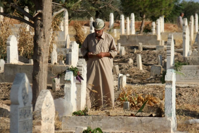 Un Syrien lit le coran sur les tombes de proches et de membres de sa famille au premier jour de l'Aïd al-Adha, la grande fête musulmane du sacrifice, le 1er septembre 2017 à Binnish (Syrie)

