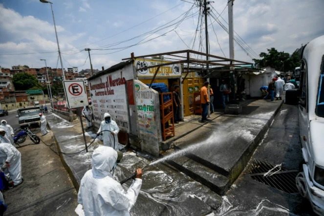 Des employés municipaux en combinaison de protection contre le coronavirus nettoient les rues de Petare, un quartier de Caracas, le 2 avril 2020 au Venezuela