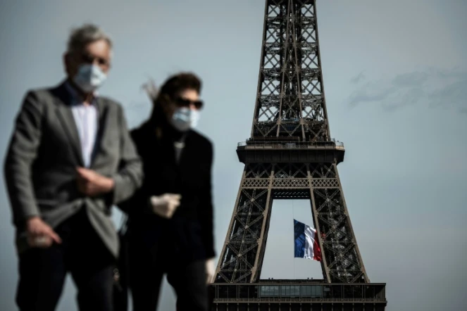 Un homme et une femme portant un masque devant la Tour Eiffel à Paris le 11 mai 2020