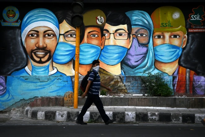 Un homme passe devant une fresque de rue représentant des personnels luttant contre le coronavirus, le 14 juillet 2020 à New Delhi