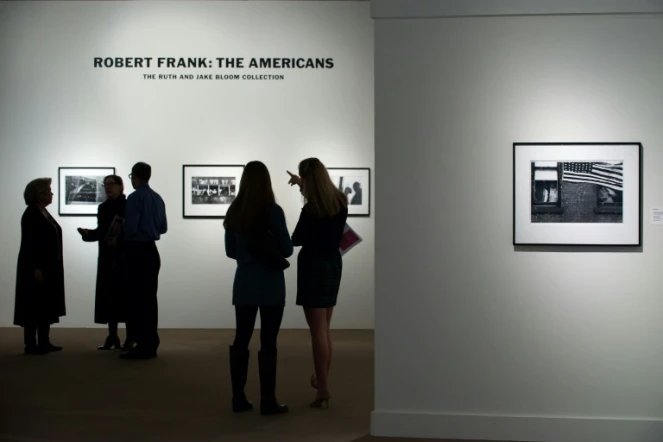 Des visiteurs regardent des images du photographe Robert Frank tirées de son livre "Les Américains", lors d'une exposition à Sotheby's à New York (Etats-Unis), le 17 décembre 2015