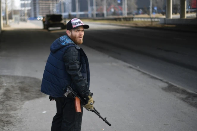 Un civil ukrainien armé d'un fusil protège une route à Kiev, le 25 février 2022