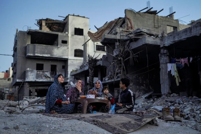 Une famille palestinienne rompt le jeûne du ramandan dans les ruines de sa maison à Deir el-Balah, dans le centre de la bande de Gaza, le 11 mars 2024
