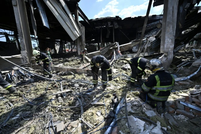 Des sauveteurs déblaient les décombres d'un centre commercial à Krementhouk, en Ukraine, le 28 juin 2022, au lendemain d'une frappe russe qui a fait au moins 18 morts, selon Kiev