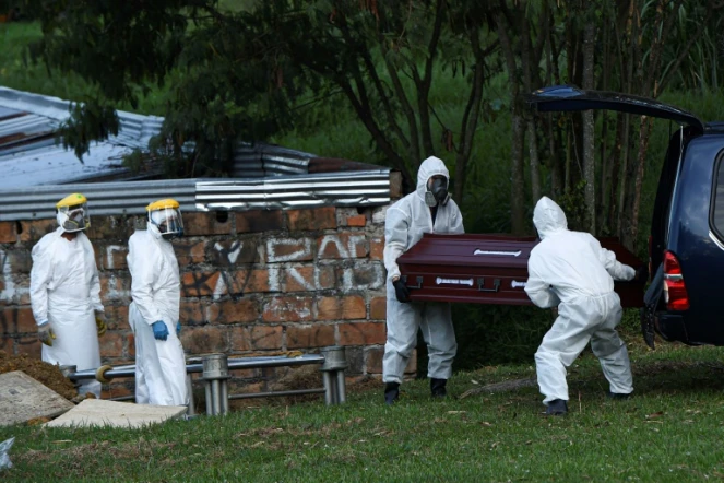 Le personnel d'un cimetière à Medellin en Colombie enterrent le cercueil d'une femme décédée du Covid-19 le 12 août 2020