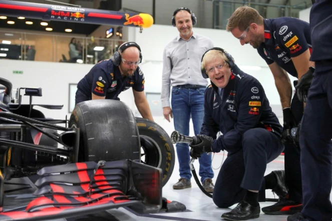 Le Premier ministre conservateur Boris Johnson change laroue d'une Formule 1 Red Bull, lors d'une visite dans le cadre de la campagne pour les législatives, à Milton Keynes au nord de Londres, le 4 décembre 2019