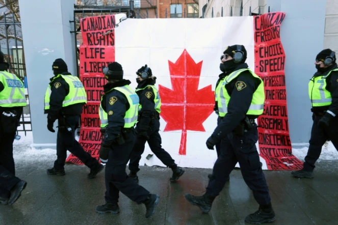 Des policiers passent devant un drapeau canadien près du Parlement à Ottawa, le 7 février 2022