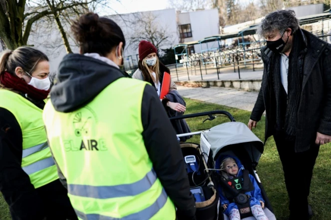 Le professeur Roeland Samson, de l'Université d'Anvers (à d.) donne des explications aux volontaires venus se promener avec Claire, une poupée équipée de capteurs pour mesurer la pollution de l'air, à Anvers (Belgique) le 25 janvier 2021.