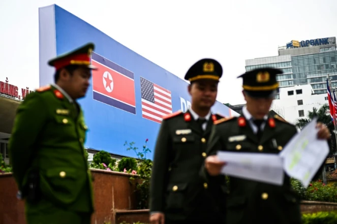 Des policiers vietnamiens devant les drapeaux nord-coréen et américain sur une affiche annonçant le prochain sommet entre les deux dirigeants, le 24 février 2019 à Hanoï