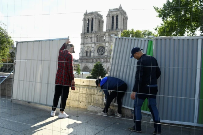 Des ouvriers installent des palissades le 13 août 2019, près de  Notre-Dame de Paris en vue de la décontamination des rues alentour de la cathédrale