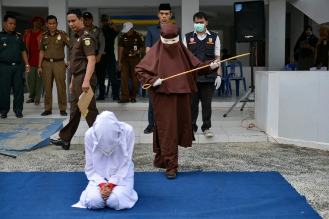Une éxécutrice sur le point de flageller en public une femme agenouillée, le 10 décembre 2019 à Aceh, en Indonésie