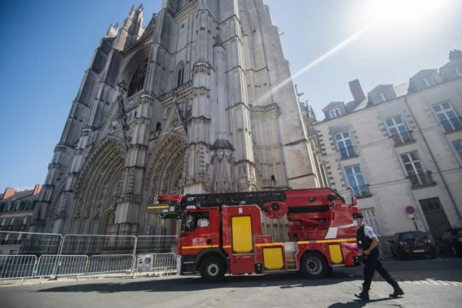 Un policier se promène devant un véhicule des pompiers stationné devant la façade partiellement brûlée de la cathédrale Saint-Pierre-et-Saint-Paul de Nantes, dans l?ouest de la France, le 20 juillet 2020