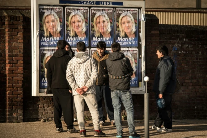 Des migrants regardent les panneaux électoraux à Calais avec en affiche la tête de liste FN de la région Nord, Marine Le Pen, le 7 décembre 2015