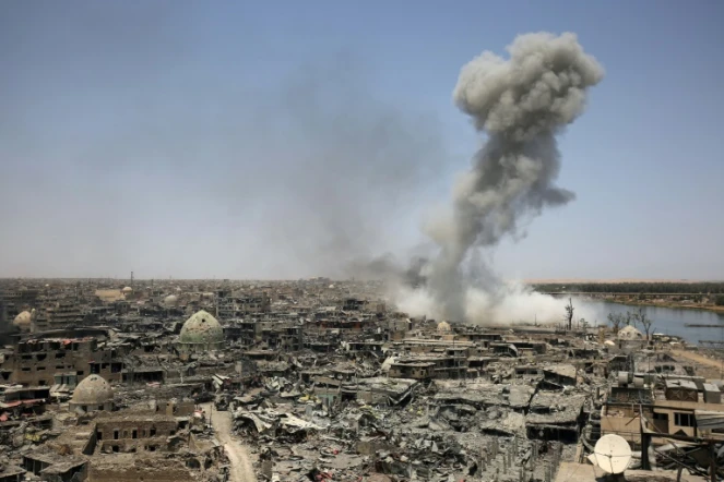 Une colonne de fumée se dégage de la ville irakienne de Mossoul après un raid de la coalition internationale dirigée par les Etats-Unis, en soutien aux forces irakiennes au sol face aux jihadistes, le 9 juillet 2017 