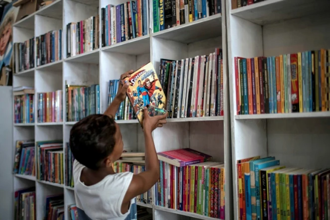 Un jeune garçon replace un livre sur une étagère de la bibliothèque "Mundo da Lua" à Rio de Janeiro