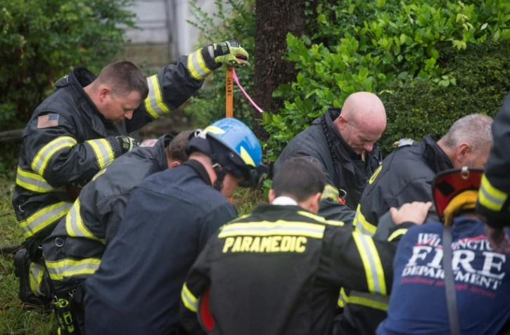Des pompiers en opération prient sur les lieux où une femme et son enfant ont été tués par la chute d'un arbre lors du passage de l'ouragan Florence, le 14 septembre 2018 à Wilmington, en Caroline du Nord