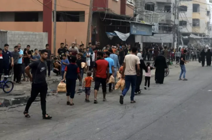 Des habitants portent des sacs de pain tandis que d'autres font la queue devant une boulangerie, le 28 octobre 2023 à Gaza ( AFP / MOHAMMED ABED )