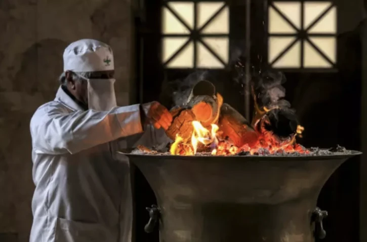 Un prêtre zoroastrien ajoute du bois au feu sacré dans le sanctuaire du temple du feu de Yazd, dans le centre de l'Iran, le 4 juillet 2023 ( AFP / ATTA KENARE )